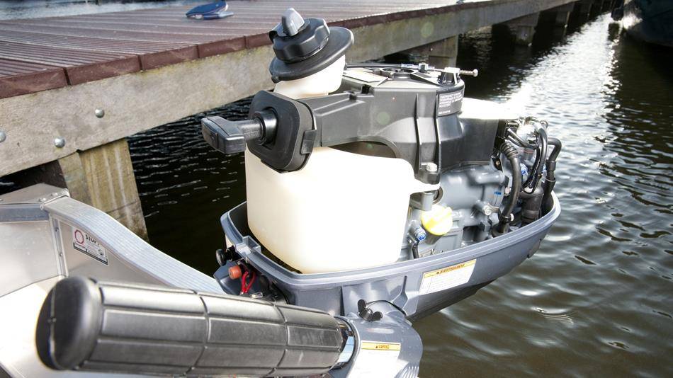 Yamaha buitenboordmotor zonder de motorkap met zicht op de interne brandstoftank en motorcomponenten, gemonteerd op een boot aan de steiger.
